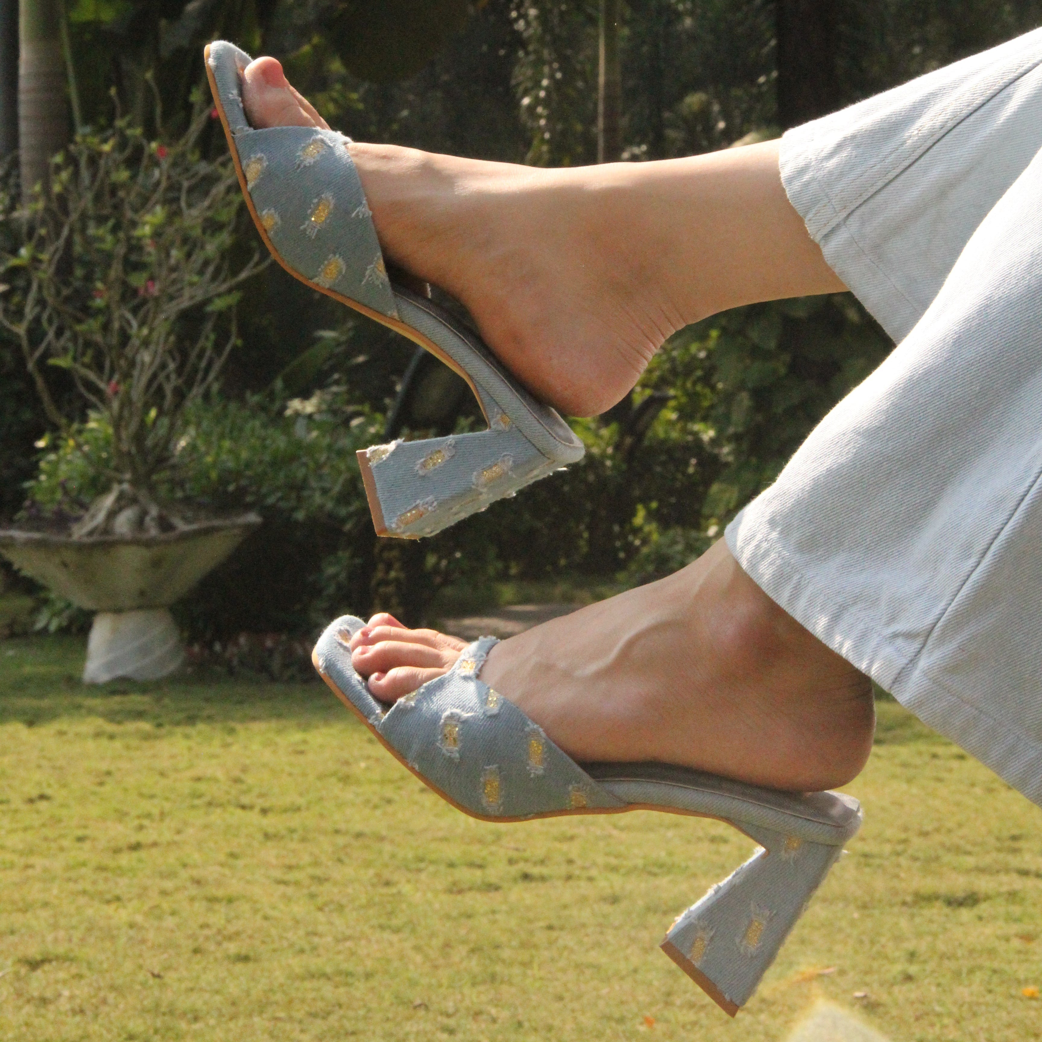 Close-up of feet wearing light blue high-heeled shoes with a natural background