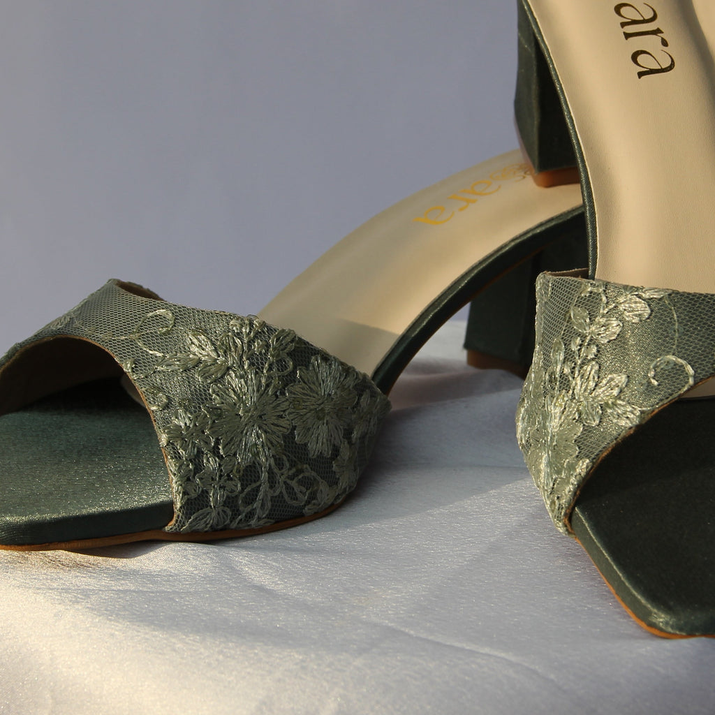 Green high-heeled shoes on a white surface with a neutral background