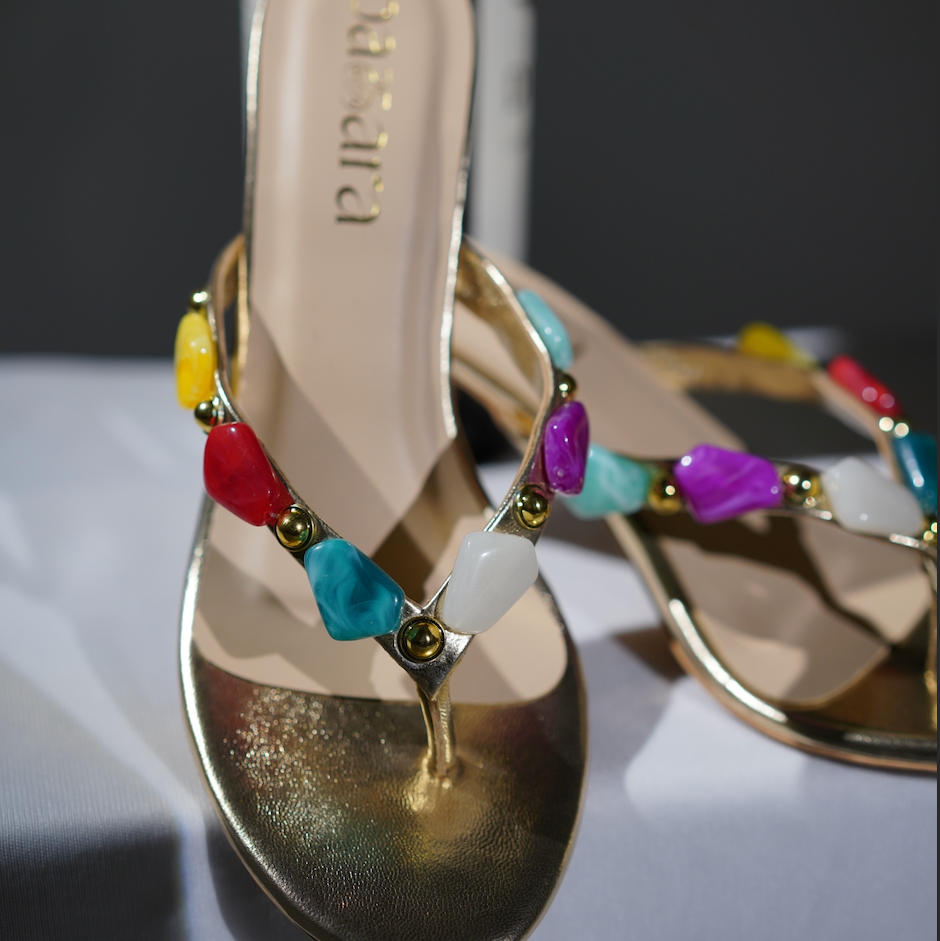 Gold sandals with colorful beading on a white surface