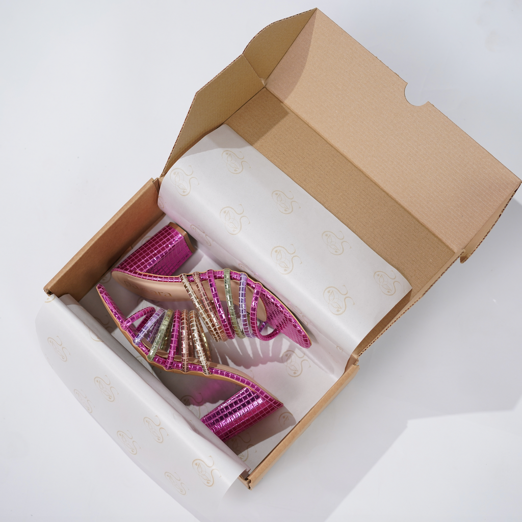 Open cardboard box with a pink sandal inside on a white background
