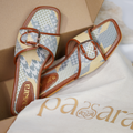 Pair of floral-patterned slippers with brown straps on a branded cloth, with 'ara' branding visible.