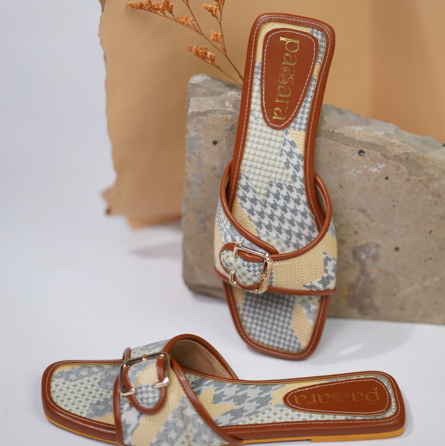 Pair of patterned sandals with brown straps on a neutral background